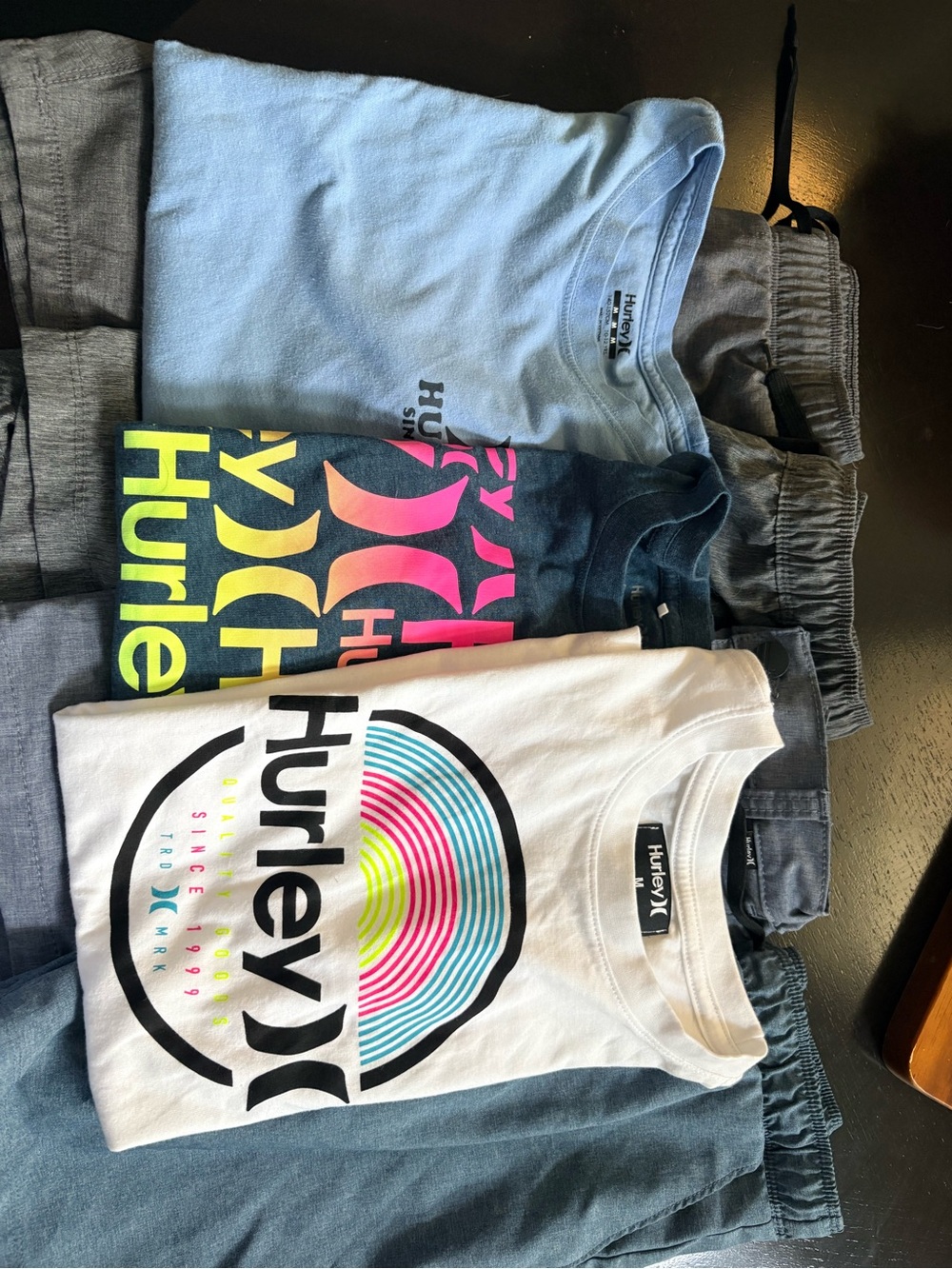Hurley Trio: White, Light Blue & Black Graphic Tees with Gray Shorts